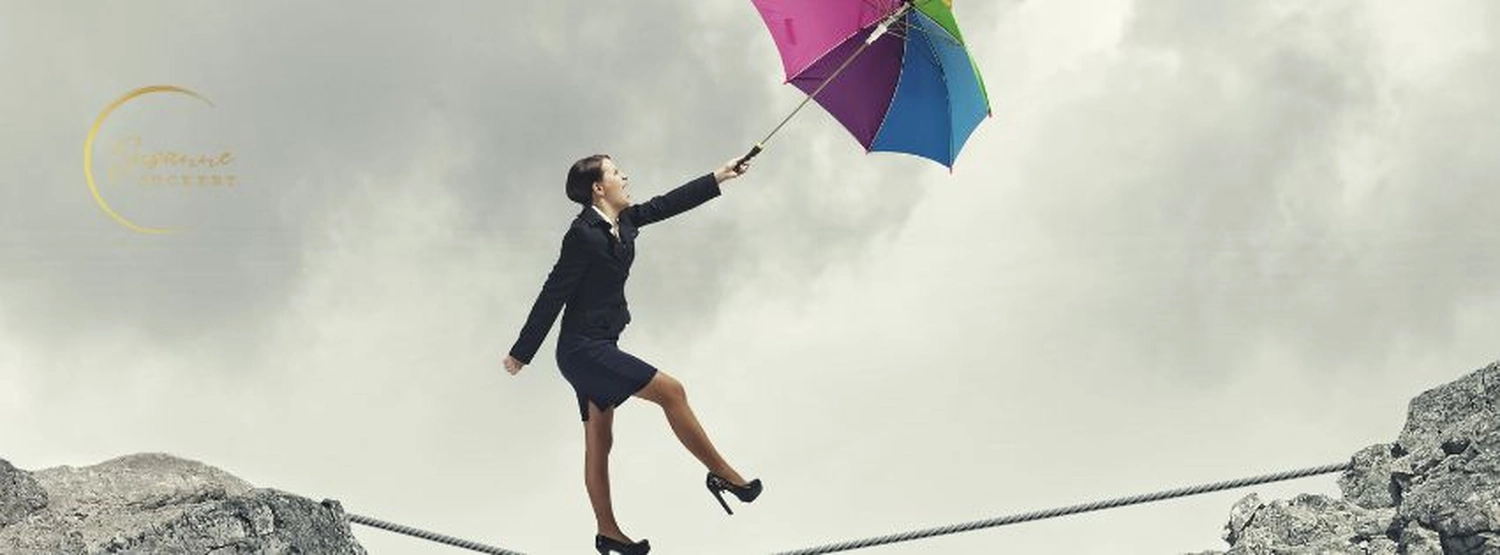 stress.coaching - Hypnose, Coaching, Seminare - Banner auf der Website von Susanne Suckert, das eine Frau in Businesskleidung mit einem bunten Regenschirm auf einem Felsgipfel zeigt.