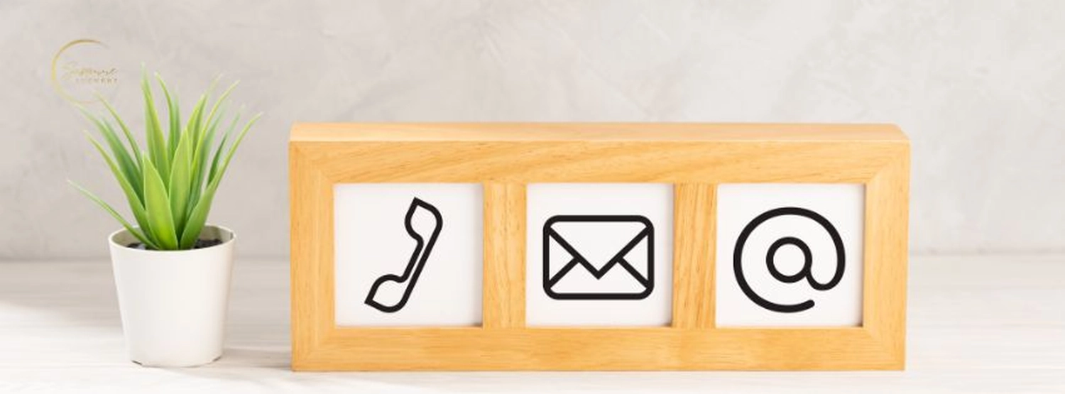 stress.coaching - Hypnose, Coaching, Seminare - Dekorativer Holzrahmen auf einem Schreibtisch mit Kontaktsymbolen neben einer kleinen Topfpflanze.